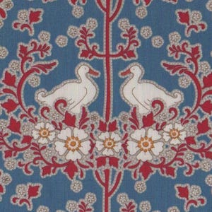 Op de afbeelding: Een herhalend patroon van witte vogels die op gestileerde bomen zitten met rode takken en witte bloemen met gele centra op een blauwe achtergrond.