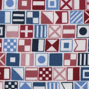 Puede incluir: Una tela con un patrón repetido de banderas de señales náuticas en rojo, blanco y azul. Las banderas cuadradas muestran varias formas y diseños geométricos, creando un tema marítimo.