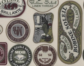 May include: A beige fabric with a repeating pattern of vintage-style labels. The labels are in various shapes and sizes, with a mix of green, brown, and red colors. The labels feature text in French and English, including "Bobine Soleil", "Mouline Double", and "BRILLANTE".