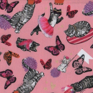 May include: Pink fabric with a repeating pattern of grey cats wearing crowns, tutus, and other accessories. Butterflies and flowers are also included in the design.