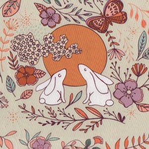 May include: A whimsical illustration featuring two white rabbits facing each other, surrounded by a colourful floral pattern with butterflies and a large orange sun. The background is a light beige.