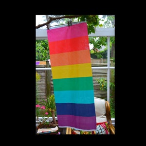 Op de afbeelding: Een regenboogkleurige stoffen banner die aan een waslijn hangt. De banner heeft zeven strepen in de kleuren rood, oranje, geel, groen, blauw, indigo en violet.