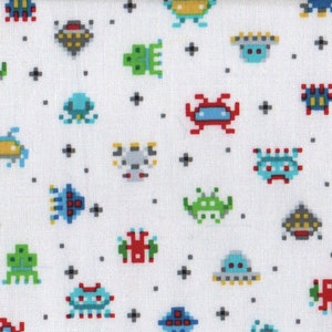May include: White fabric with a repeating pattern of colorful pixelated alien and spaceship designs. The aliens are green, red, blue, and gray. The spaceships are blue, yellow, and gray.