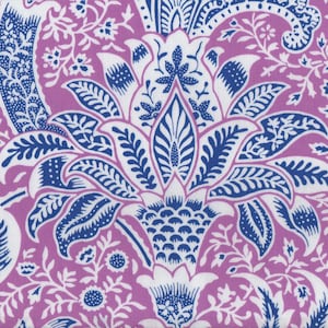 Puede incluir: Una tela con un estampado floral que presenta una flor central estilizada en blanco y azul sobre un fondo lavanda. El diseño incluye intrincados motivos de hojas y flores, creando un textil detallado y decorativo.