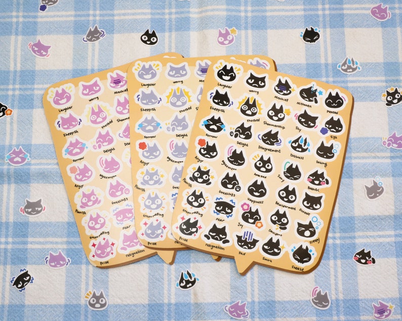 May include: Three sheets of stickers featuring black and white illustrations of cats with different emotions. The stickers are on a light blue and white checkered background. The emotions include: angry, sleepy, worried, shy, scared, happy, surprised, and more.
