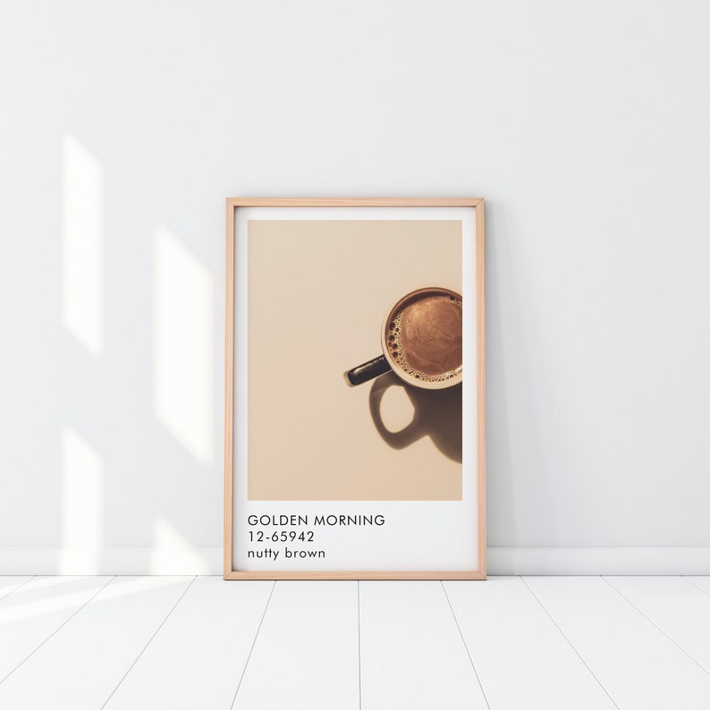 May include: A framed print of a coffee cup with a light brown background. The text on the print reads "GOLDEN MORNING 12-65942 nutty brown".