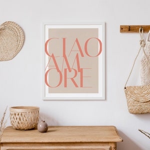 May include: A white framed print with a beige background and the text "CIAO AMORE" in coral pink.