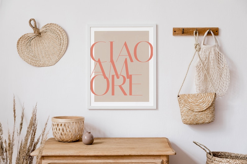May include: A white framed print with a beige background and the text "CIAO AMORE" in coral pink.