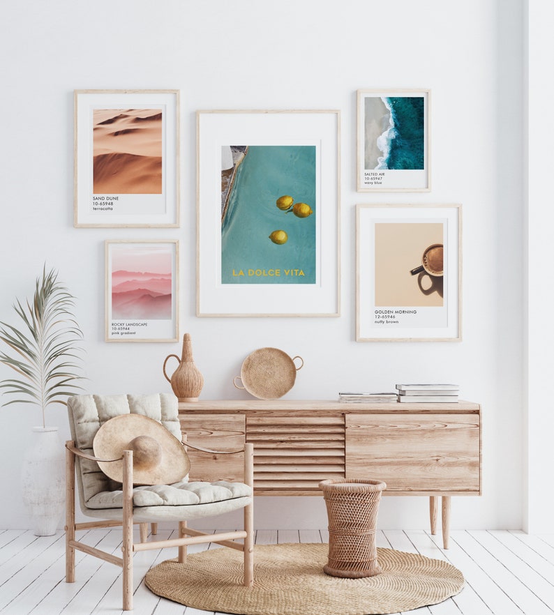 May include: A living room interior with a wooden console table and a chair. The wall is decorated with framed prints featuring a desert landscape, a pool with lemons, a beach scene, a mountain range, and a cup of coffee. The text on the prints reads "Sand Dune 10.45948", "La Dolce Vita", "Salted Air 10.45948", "Misty Landscapes 10.45948", and "Golden Morning 10.45948".