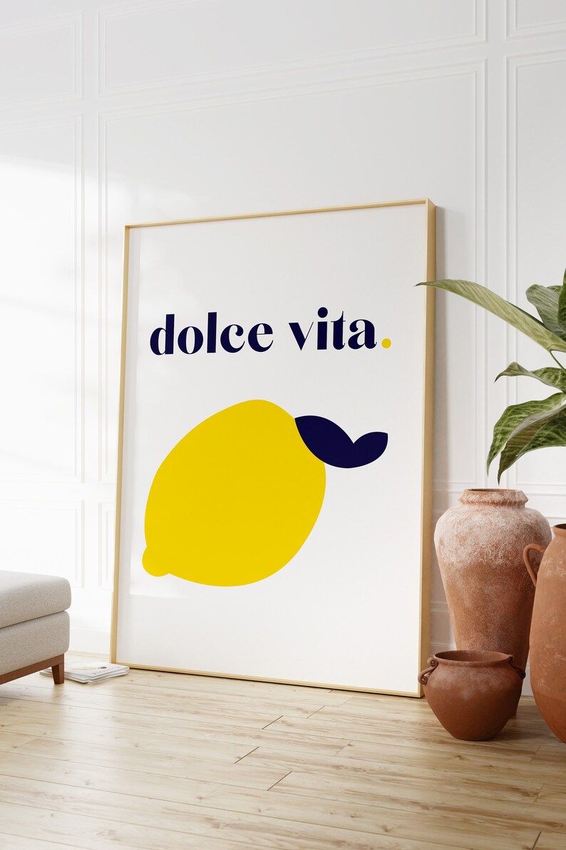 Puede incluir: Un cuadro enmarcado con una ilustraci&oacute;n de un lim&oacute;n amarillo y la frase "dolce vita" en azul marino. La obra de arte est&aacute; en un marco dorado. Una elegante pieza de arte mural para la cocina o el sal&oacute;n.