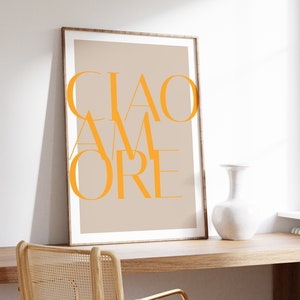 May include: A framed print with the text "CIAO AMORE" in orange on a beige background. The print is hanging on a wall above a wooden desk with a chair.