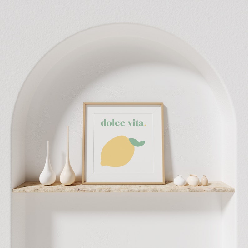 May include: A framed print with a yellow lemon and the text "dolce vita." The print is on a wooden shelf with white ceramic vases.