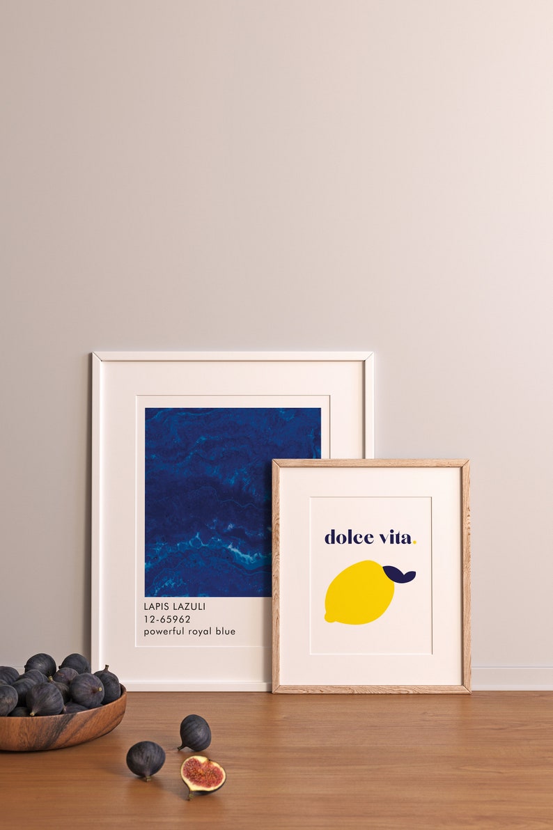 Puede incluir: Dos impresiones art&iacute;sticas enmarcadas. Una presenta un dise&ntilde;o abstracto azul profundo con el texto "Lapis Lazuli 12-65962 powerful royal blue". La otra impresi&oacute;n tiene una ilustraci&oacute;n de lim&oacute;n amarillo con las palabras "dolce vita."