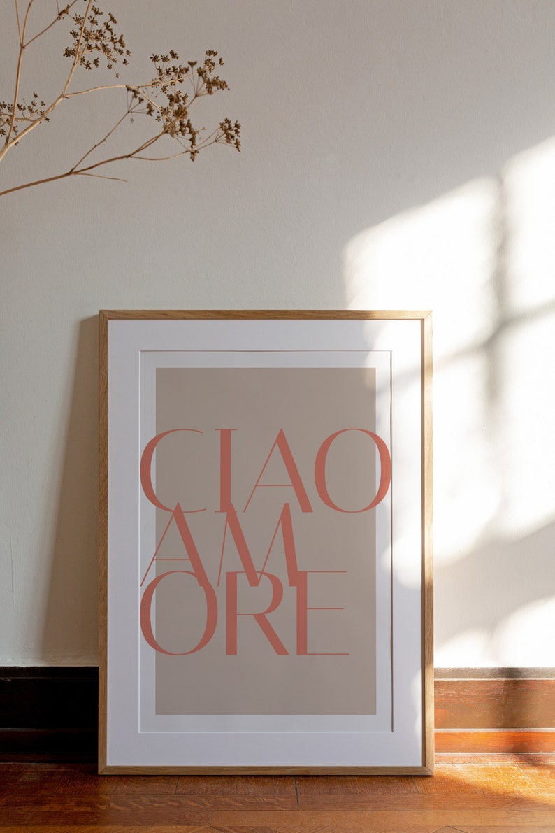 May include: A framed print with a beige background and the text "CIAO AMORE" in a coral pink color.