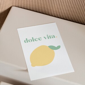 May include: A white card with the text "dolce vita." printed in green. A yellow lemon with a green stem is illustrated below the text.