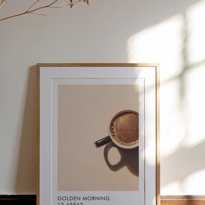 May include: A framed print with a photo of a cup of coffee. The text on the print reads "GOLDEN MORNING 12-65942 nutty brown".