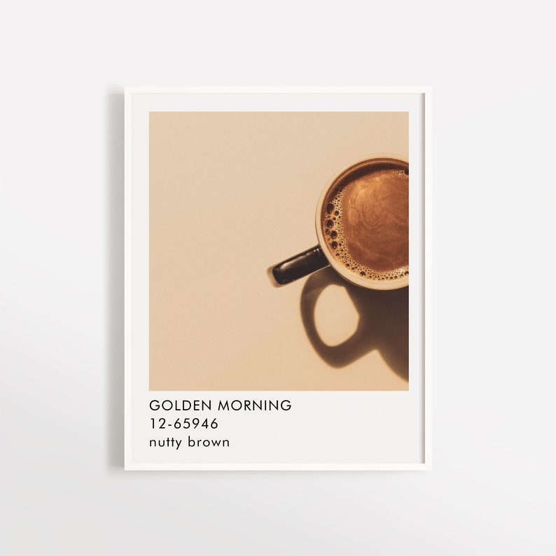 May include: A close-up of a cup of coffee with a light brown background. The coffee is a dark brown color and has a creamy foam on top. The text "GOLDEN MORNING 12-65946 nutty brown" is below the cup.