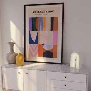 Op de afbeelding: Een ingelijste kunstprint getiteld "COLLAGE SERIE" met een abstract ontwerp in diverse kleuren, waaronder blauw, roze en oranje. De print wordt getoond boven een witte kast met gouden knoppen, samen met een decoratieve lamp en vazen.
