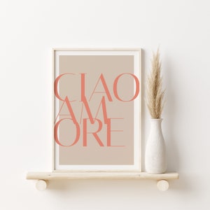 May include: A framed print with a beige background and the text "CIAO AMORE" in coral pink.