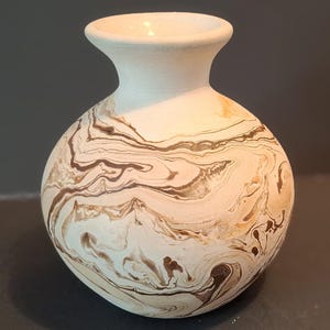May include: A small, white ceramic vase with a brown and white marbled design.