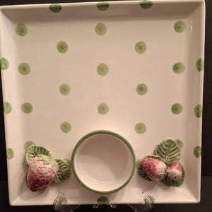 Puede incluir: Plato cuadrado de cerámica para servir con fondo blanco y lunares verdes. El plato tiene un cuenco central y está decorado con detalles de fresas y hojas en 3D. El borde del cuenco es verde.