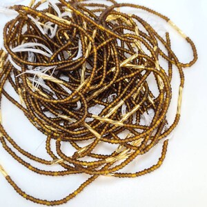 May include: A pile of brown glass beads with gold spacers. The beads are small and round, and the spacers are long and thin.