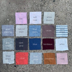 May include: A collection of 16 fabric swatches in various colors and patterns, including white, gray, blue, beige, coral, rose, lilac, and brown. The swatches are arranged in a grid pattern on a gray concrete surface. Each swatch has a label with a descriptive name, such as "soft rose", "white square", "blue jeans", and "natural linen".