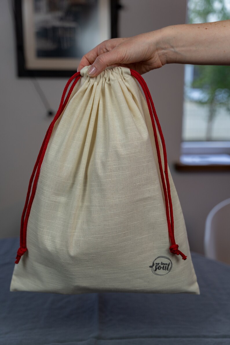 May include: A white drawstring bag with red drawstrings and a black logo that says "my own soul".