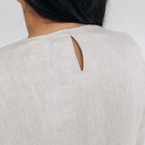 K&ouml;nnte beinhalten: Ein hellbeiges Leinenkleid mit einem Schl&uuml;ssellochausschnitt im R&uuml;cken.