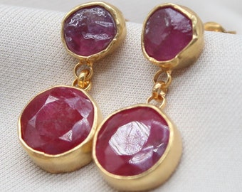 May include: Gold earrings with two round pink gemstones. The earrings have a dangling design.