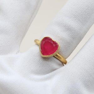May include: A gold ring with a heart-shaped pink gemstone.