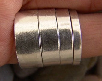 May include: A silver ring made of multiple stacked bands. The ring is worn on a finger and is shown against a background of small, gray stones.