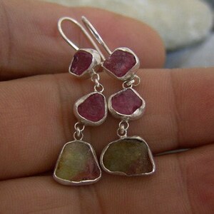Op de afbeelding: Zilveren oorbellen met roze en groene edelsteen druppels. De oorbellen hebben drie druppelvormige edelstenen aan elke oorbel.