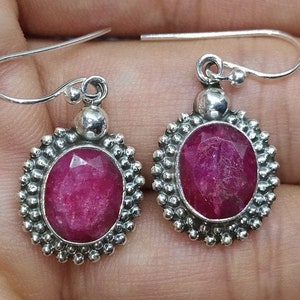 Peut inclure: Une paire de boucles d'oreilles en argent avec une pierre ovale rose sertie dans une bélière en argent. Les boucles d'oreilles ont une bordure perlée et une fermeture simple à crochet.