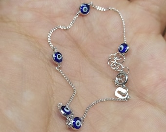May include: A silver chain bracelet with four blue evil eye charms. The bracelet has a lobster clasp closure.