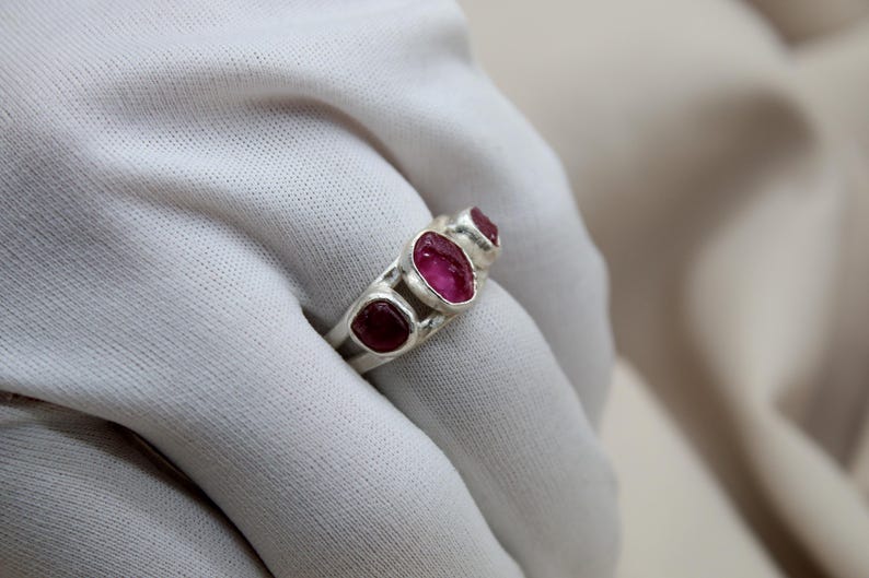 Pu&ograve; includere: Un anello d'argento con tre pietre ovali rosa incastonate in una fascia.