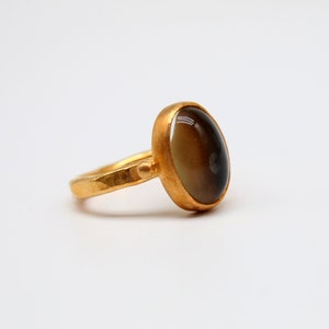 May include: A gold ring with a dark brown oval gemstone.