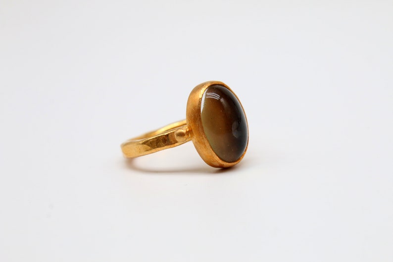 May include: A gold ring with a dark brown oval gemstone.