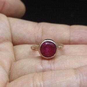 Pu&ograve; includere: Un anello d'argento con una pietra preziosa di rubino rosso incastonata in una montatura a castone.