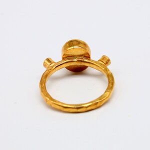 Peut inclure: Une bague en or avec une pierre ronde textur&eacute;e. La bague a deux petits accents ronds de chaque c&ocirc;t&eacute; de la pierre.