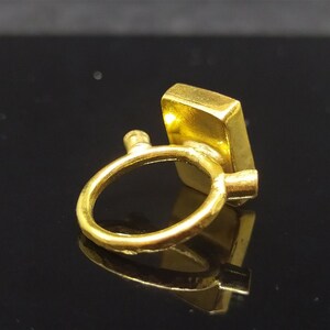 Op de afbeelding: Gouden ring met een rechthoekige edelsteen. De ring is simpel en elegant.