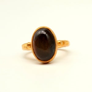 May include: A gold ring with a dark brown oval gemstone.
