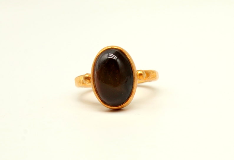 May include: A gold ring with a dark brown oval gemstone.