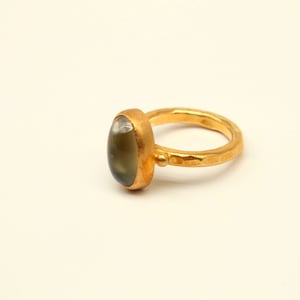 May include: A gold ring with a green oval gemstone set in a hammered band.