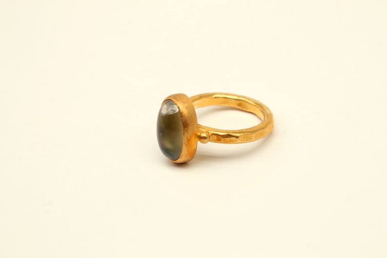 May include: A gold ring with a green oval gemstone set in a hammered band.