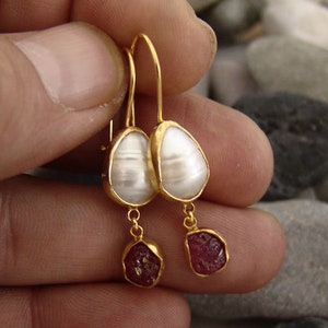 May include: Gold earrings with white pearl-like drops and red gemstone accents.
