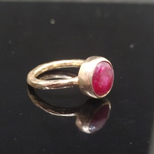 Pu&ograve; includere: Un anello d'oro con una fascia martellata e una pietra preziosa rotonda di rubino rosso.