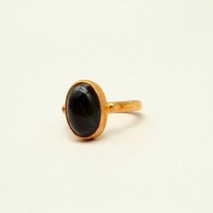 May include: A gold ring with a black oval gemstone.