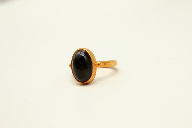 May include: A gold ring with a black oval gemstone.