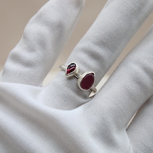 May include: A silver ring with two teardrop-shaped red gemstones.